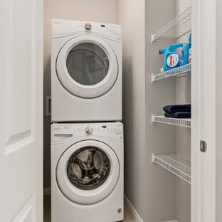 Inspiration for a small contemporary laundry cupboard in Calgary with grey walls, a stacked washer and dryer and lino flooring.