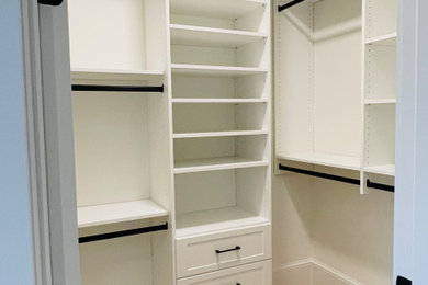 Diseño de armario vestidor unisex clásico renovado de tamaño medio con armarios estilo shaker, puertas de armario blancas y suelo de madera clara