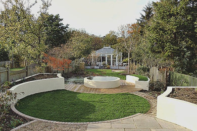 Modelo de jardín moderno de tamaño medio en verano en patio trasero con jardín francés, estanque, exposición total al sol, adoquines de piedra natural y con madera