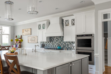 Inspiration for a large transitional l-shaped medium tone wood floor open concept kitchen remodel in Raleigh with a farmhouse sink, flat-panel cabinets, white cabinets, quartz countertops, blue backsplash, glass tile backsplash, stainless steel appliances and an island