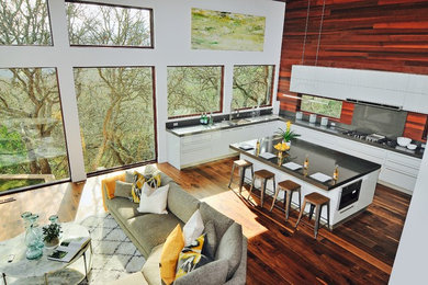 Inspiration for a huge contemporary u-shaped dark wood floor eat-in kitchen remodel in Nice with a drop-in sink, flat-panel cabinets, gray cabinets, solid surface countertops, gray backsplash, wood backsplash, stainless steel appliances and an island