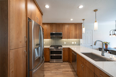 Minimalist vinyl floor and brown floor kitchen photo in Salt Lake City with an undermount sink, flat-panel cabinets, medium tone wood cabinets, quartzite countertops, green backsplash, porcelain backsplash, stainless steel appliances and white countertops