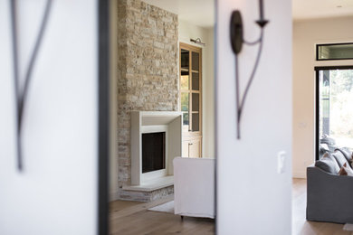 Diseño de salón contemporáneo grande con paredes beige, suelo de madera clara, estufa de leña y marco de chimenea de hormigón