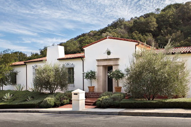 Large mediterranean one-storey stucco white house exterior in Los Angeles with a gable roof and a tile roof.