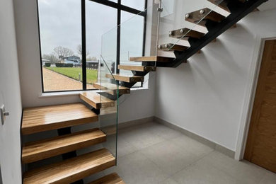 Inspiration for a medium sized contemporary wood floating metal railing staircase in Hampshire with wood risers.