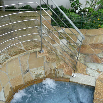 Hot Tub Nestled Between Staircase Built from Flagstone and Stainless Steel Raili