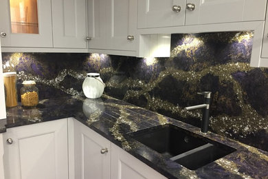 Inspiration for a medium sized modern l-shaped kitchen/diner in Other with a built-in sink, white cabinets, quartz worktops, multi-coloured splashback, stone slab splashback, black appliances, laminate floors, an island, brown floors and multicoloured worktops.