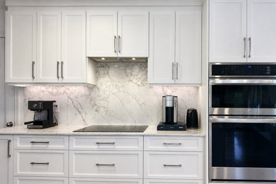 Eat-in kitchen - large modern single-wall light wood floor and brown floor eat-in kitchen idea in Montreal with shaker cabinets, white cabinets, quartz countertops, white backsplash, quartz backsplash, stainless steel appliances, an island, white countertops and an undermount sink