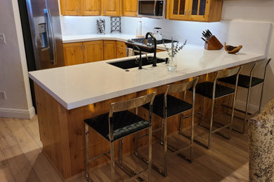 Mid-sized u-shaped vinyl floor kitchen photo in Salt Lake City with an undermount sink, recessed-panel cabinets, light wood cabinets, quartzite countertops, white backsplash, quartz backsplash, stainless steel appliances, a peninsula and white countertops
