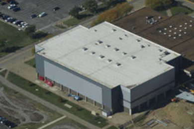 Ejemplo de fachada beige industrial de tamaño medio de tres plantas con revestimiento de hormigón, tejado plano y tejado de varios materiales