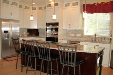 Mid-sized trendy l-shaped light wood floor and brown floor enclosed kitchen photo in Denver with an undermount sink, shaker cabinets, white cabinets, granite countertops, multicolored backsplash, mosaic tile backsplash, stainless steel appliances and an island
