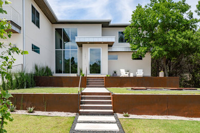 Réalisation d'une façade de maison beige design en stuc de taille moyenne et à un étage avec un toit plat, un toit en métal et un toit gris.