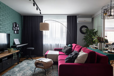 На фото: маленькая открытая гостиная комната с музыкальной комнатой, зелеными стенами, паркетным полом среднего тона, отдельно стоящим телевизором, обоями на стенах и бордовым диваном