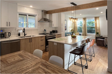 Inspiration for a mid-sized contemporary single-wall medium tone wood floor, brown floor and exposed beam eat-in kitchen remodel in Montreal with a single-bowl sink, flat-panel cabinets, white cabinets, solid surface countertops, white backsplash, subway tile backsplash, stainless steel appliances, an island and white countertops