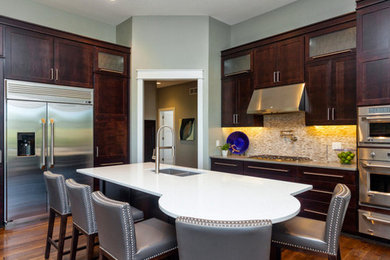 Large transitional l-shaped medium tone wood floor eat-in kitchen photo in Other with an undermount sink, shaker cabinets, dark wood cabinets, granite countertops, beige backsplash, mosaic tile backsplash, stainless steel appliances and an island