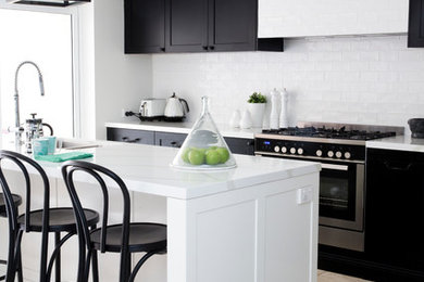 This is an example of a contemporary open plan kitchen in Sydney with black floor.