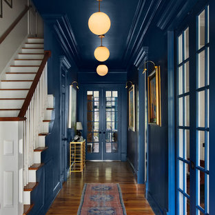 Bild på en stor vintage hall, med blå väggar, mellanmörkt trägolv och brunt golv