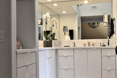 Inspiration for a mid-sized modern master gray tile medium tone wood floor and brown floor drop-in bathtub remodel in Los Angeles with flat-panel cabinets, white cabinets, a one-piece toilet, gray walls, a drop-in sink, quartz countertops and white countertops