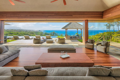 Large contemporary open concept living room in Hawaii with beige walls, dark hardwood floors, no fireplace and brown floor.