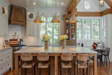 Example of a large classic l-shaped medium tone wood floor, brown floor and shiplap ceiling eat-in kitchen design in New York with a farmhouse sink, recessed-panel cabinets, white cabinets, marble countertops, white backsplash, glass tile backsplash, stainless steel appliances, an island and beige countertops