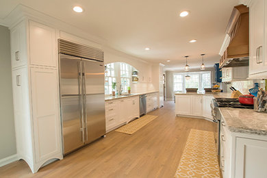 Open concept kitchen - large traditional galley light wood floor open concept kitchen idea in Other with an undermount sink, beaded inset cabinets, white cabinets, quartzite countertops, white backsplash, subway tile backsplash, stainless steel appliances and a peninsula