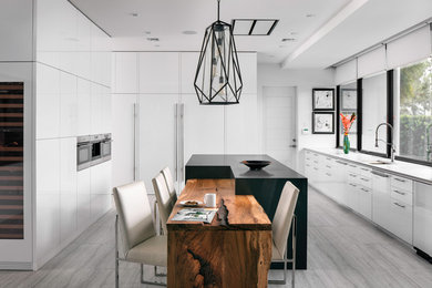 Contemporary u-shaped kitchen in Orlando with an undermount sink, flat-panel cabinets, white cabinets, window splashback, panelled appliances, with island, grey floor and white benchtop.