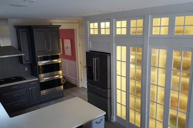 Mid-sized trendy u-shaped gray floor enclosed kitchen photo in New York with a drop-in sink, gray cabinets, gray backsplash, stainless steel appliances, raised-panel cabinets, quartzite countertops and a peninsula