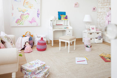 Large transitional kids' playroom in Other with white walls and medium hardwood floors for kids 4-10 years old and girls.