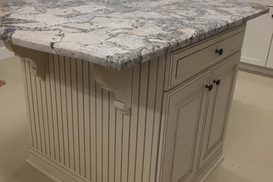 Kitchen pantry - mid-sized traditional single-wall kitchen pantry idea in Miami with raised-panel cabinets, white cabinets, granite countertops and no island