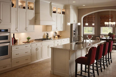 Inspiration for a mid-sized timeless single-wall ceramic tile and brown floor eat-in kitchen remodel in New York with an undermount sink, raised-panel cabinets, beige cabinets, granite countertops, beige backsplash, stainless steel appliances, an island and brown countertops