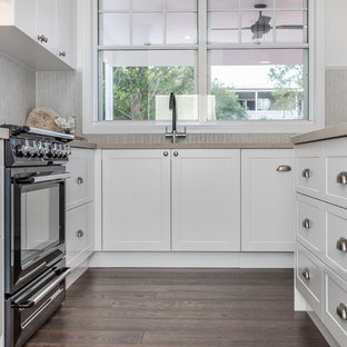 Mittelgroße Klassische Küche mit Vorratsschrank, Doppelwaschbecken, Schrankfronten im Shaker-Stil, weißen Schränken, Quarzwerkstein-Arbeitsplatte, Küchenrückwand in Beige, Rückwand aus Keramikfliesen, schwarzen Elektrogeräten, Kücheninsel, braunem Boden und rosa Arbeitsplatte in Brisbane