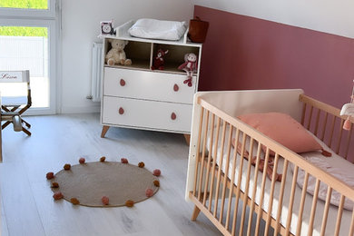 Cette photo montre une petite chambre de bébé fille scandinave avec un mur rose, parquet clair et un sol blanc.