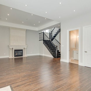 Large look-out basement in Toronto with beige walls, dark hardwood flooring, brown floors, a standard fireplace and a concrete fireplace surround.