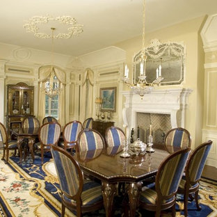 На фото: огромная гостиная-столовая в классическом стиле с бежевыми стенами, темным паркетным полом, стандартным камином и фасадом камина из штукатурки с