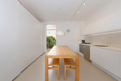Medium sized contemporary galley kitchen/diner in London with a single-bowl sink, recessed-panel cabinets, white cabinets, laminate countertops, white splashback, ceramic splashback, stainless steel appliances, lino flooring, no island, beige floors and white worktops.