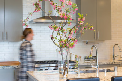 Eat-in kitchen - mid-sized modern u-shaped medium tone wood floor eat-in kitchen idea in San Francisco with an undermount sink, flat-panel cabinets, gray cabinets, granite countertops, white backsplash, glass tile backsplash, stainless steel appliances and an island