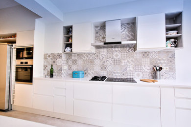 Open concept kitchen - mid-sized modern galley ceramic tile and beige floor open concept kitchen idea in Brussels with a double-bowl sink, flat-panel cabinets, beige cabinets, quartzite countertops, multicolored backsplash, ceramic backsplash, stainless steel appliances, an island and beige countertops