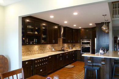 Inspiration for a mid-sized contemporary galley medium tone wood floor eat-in kitchen remodel in Nashville with a double-bowl sink, flat-panel cabinets, dark wood cabinets, quartzite countertops, beige backsplash, stone tile backsplash, stainless steel appliances and a peninsula