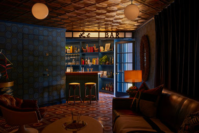 Example of an eclectic concrete floor wet bar design in Los Angeles with a drop-in sink and blue cabinets