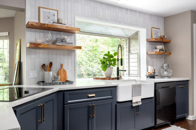 Inspiration for a mid-sized transitional l-shaped dark wood floor eat-in kitchen remodel in Seattle with a farmhouse sink, shaker cabinets, blue cabinets, quartz countertops, white backsplash, porcelain backsplash, stainless steel appliances and a peninsula