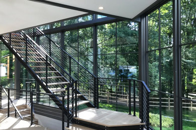 Photo of a modern wood l-shaped wire cable railing staircase in New York with open risers.