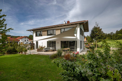 Zweistöckiges Modernes Einfamilienhaus mit Mix-Fassade, weißer Fassadenfarbe, Satteldach, Ziegeldach und rotem Dach in München