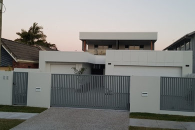 This is an example of a large modern two-storey concrete white house exterior in Gold Coast - Tweed with a flat roof and a metal roof.
