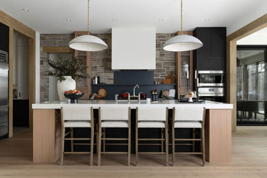 Inspiration for a large contemporary l-shaped light wood floor eat-in kitchen remodel in Toronto with a double-bowl sink, flat-panel cabinets, black cabinets, soapstone countertops, stainless steel appliances, an island and multicolored countertops