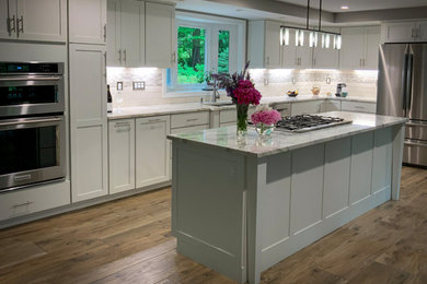 Inspiration for a large contemporary kitchen/diner in Boston with a submerged sink, shaker cabinets, white cabinets, marble worktops, white splashback, porcelain splashback, stainless steel appliances, porcelain flooring, an island, brown floors, white worktops and a coffered ceiling.