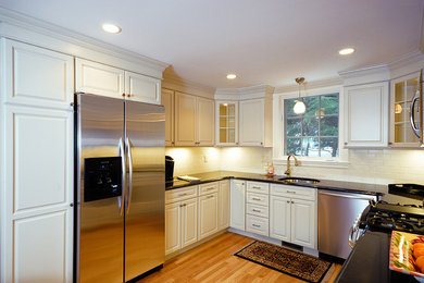 Example of a mid-sized arts and crafts u-shaped light wood floor and beige floor eat-in kitchen design in Boston with an undermount sink, raised-panel cabinets, white cabinets, granite countertops, stainless steel appliances, no island, white backsplash and subway tile backsplash
