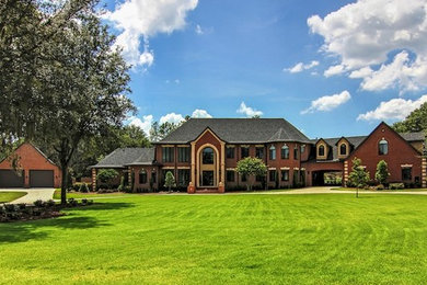 Huge traditional red three-story brick exterior home idea in Denver