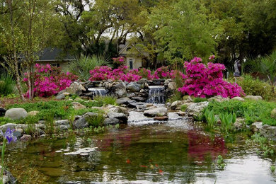 This is an example of a large traditional partial sun backyard stone landscaping in Charleston.