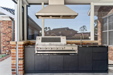 Photo of a mid-sized transitional backyard and ground level deck in Sydney with an outdoor kitchen and a roof extension.