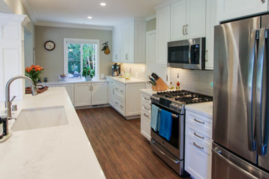 サンフランシスコにある高級な広いトランジショナルスタイルのおしゃれなキッチン (アンダーカウンターシンク、落し込みパネル扉のキャビネット、白いキャビネット、クオーツストーンカウンター、グレーのキッチンパネル、サブウェイタイルのキッチンパネル、シルバーの調理設備、クッションフロア、茶色い床、白いキッチンカウンター) の写真